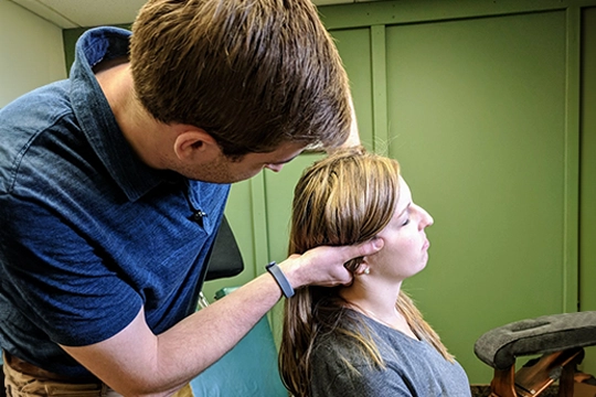 Chiropractor Grand Rapids MI Connor Knapp Adjusting Patients Neck